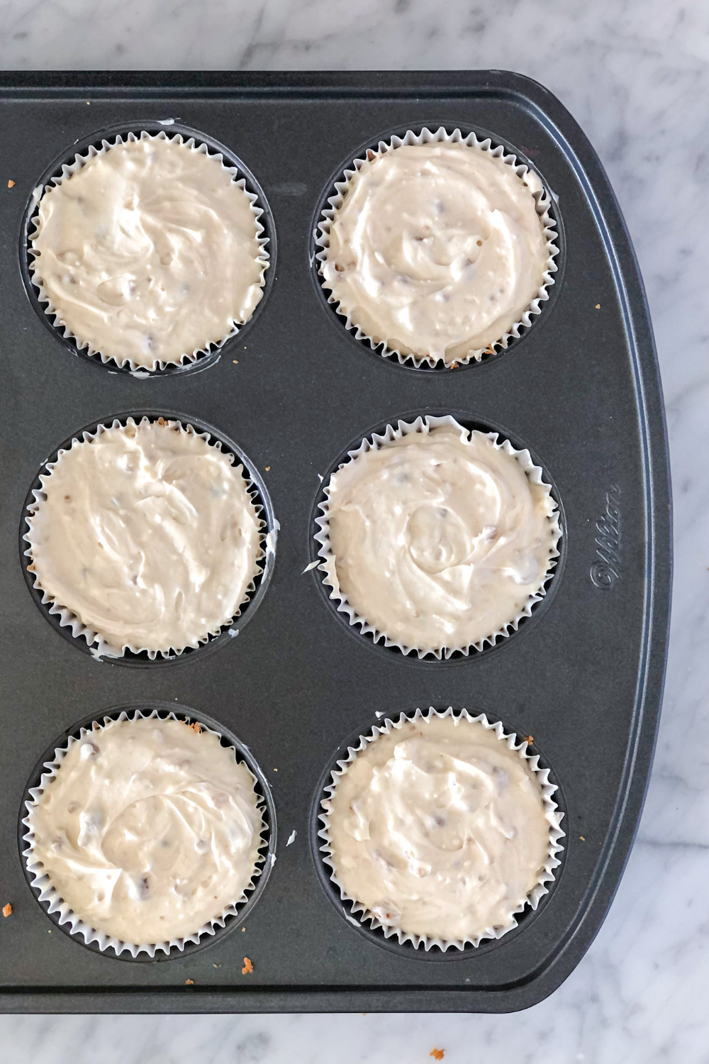 muffin tin wells filled with cheesecake filling