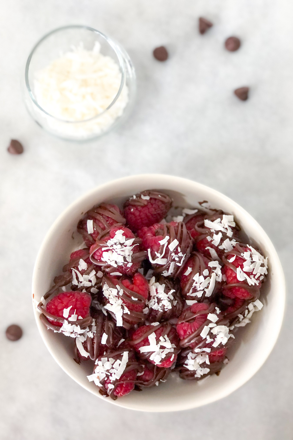 dark chocolate filled raspberries with shredded coconut in a white bowl