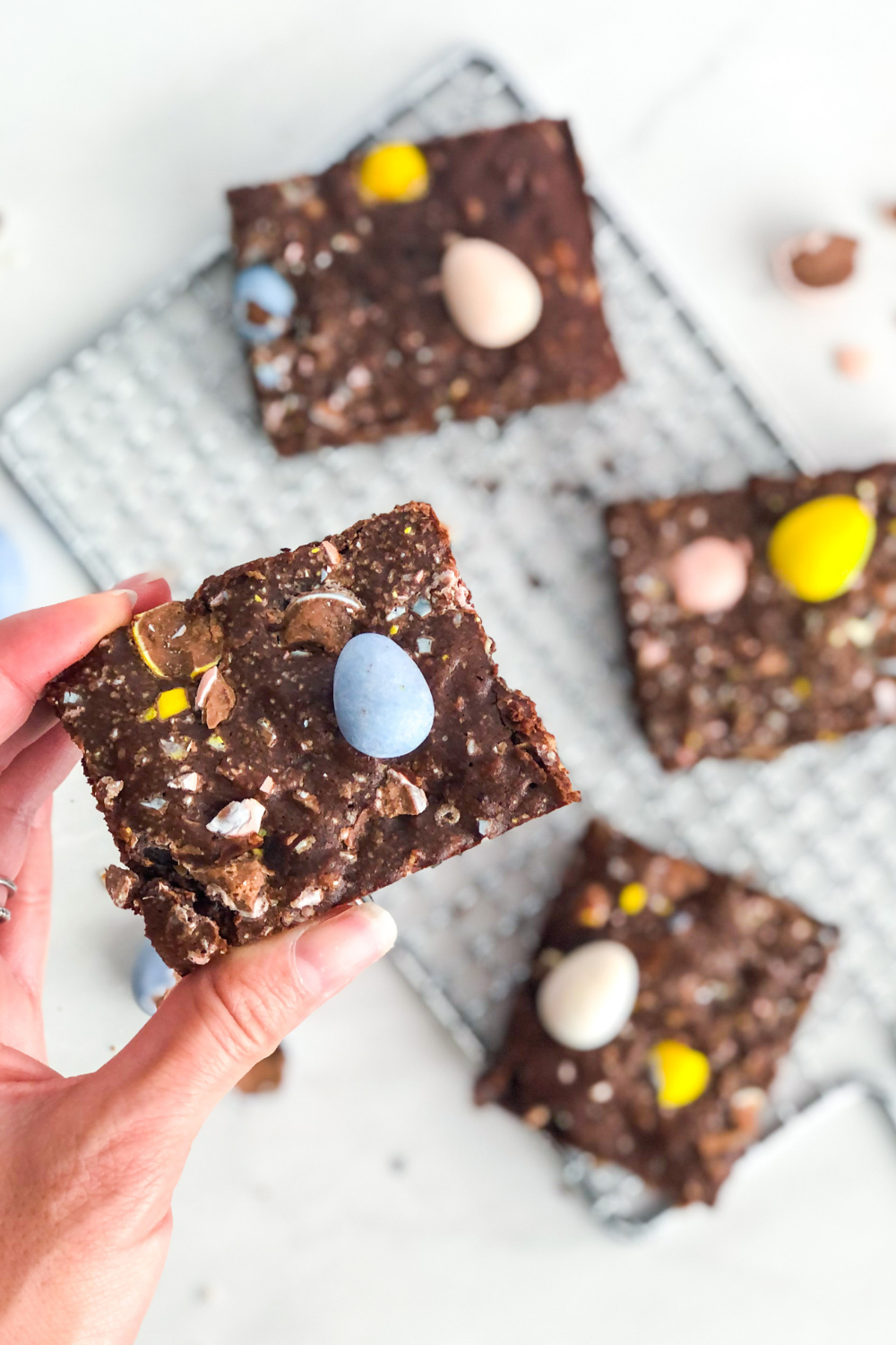 a mini egg brownie being held up above more brownies