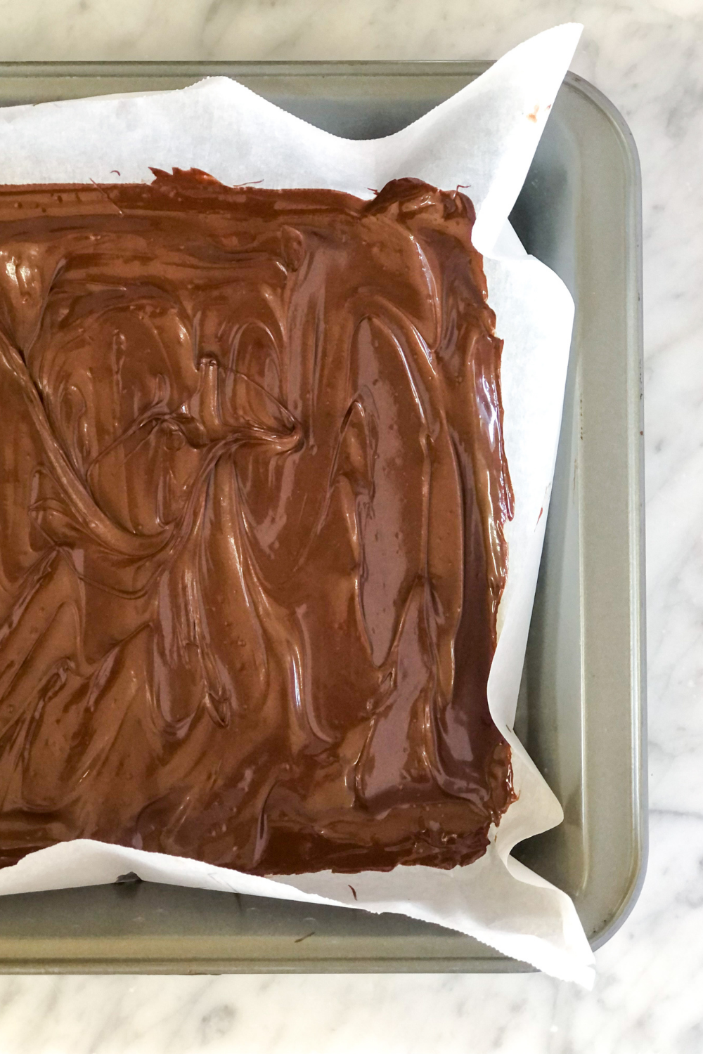 melted chocolate spread on parchment paper in a baking pan