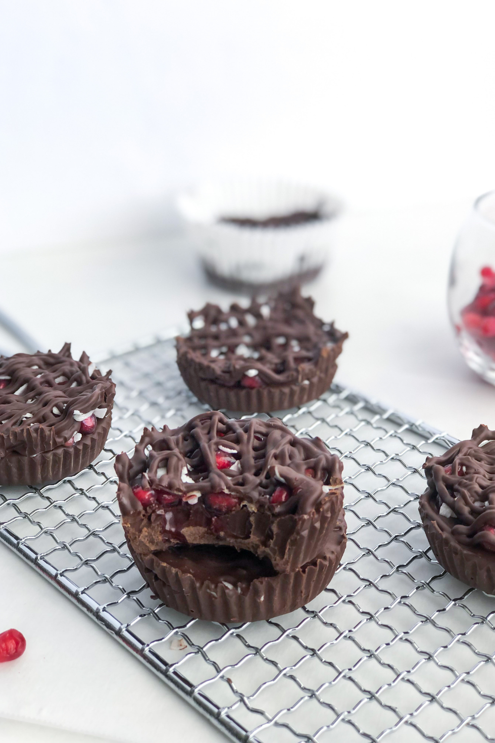 stack of dark chocolate pomegranate cups on a wire rack