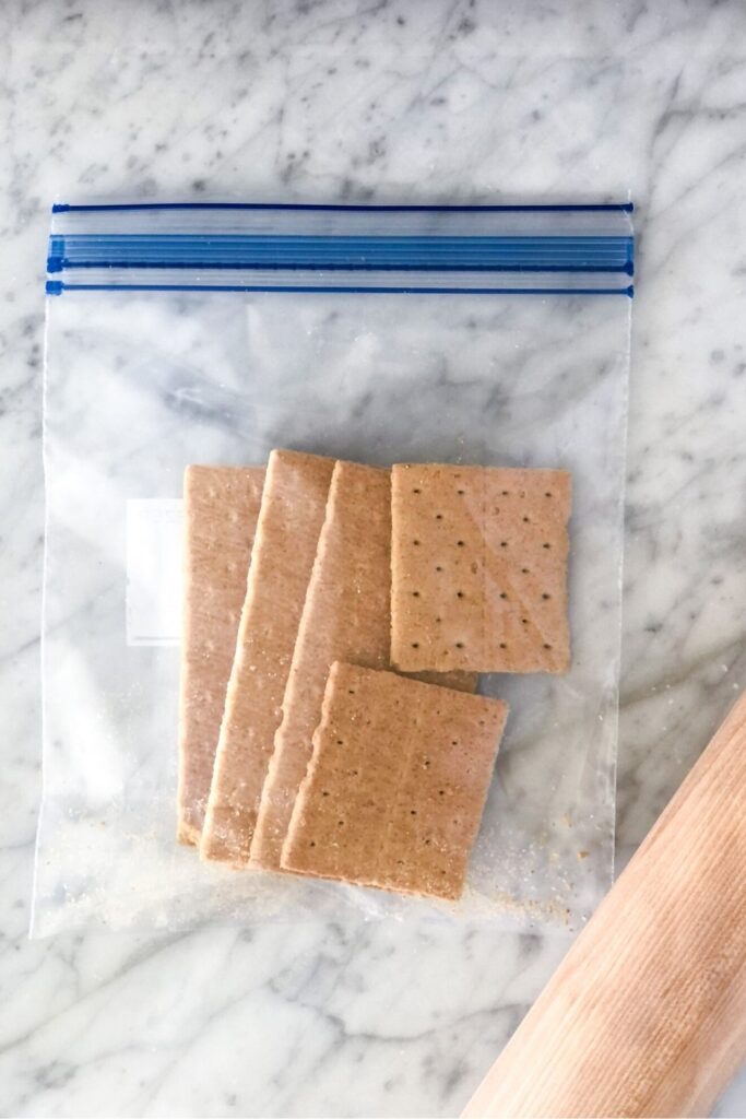 graham crackers in a ziploc bag with a rolling pin beside it