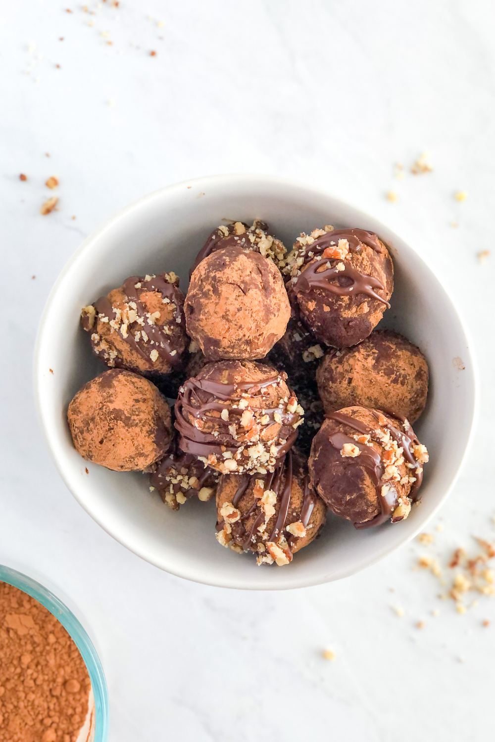 dark chocolate avocado truffles topped with chopped pecans in a white bowl