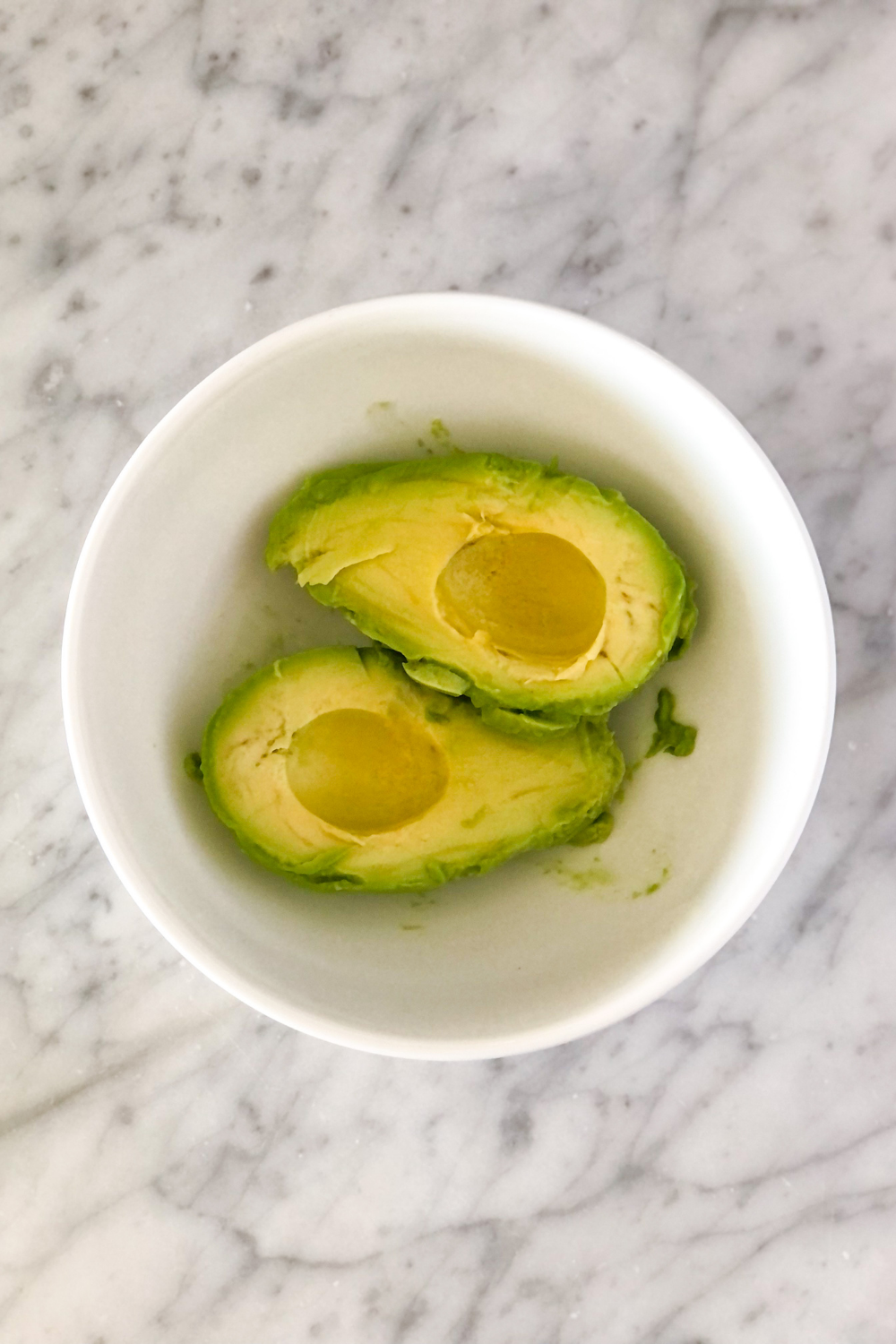 two avocado halves in a white bowl