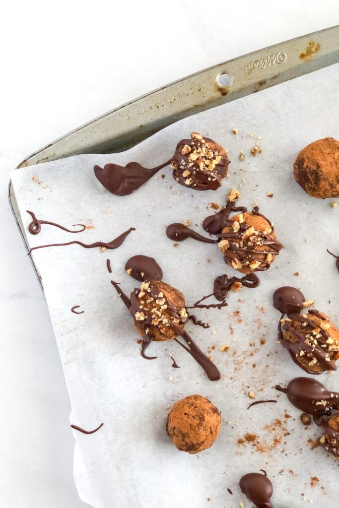 chocolate avocado truffles on a sheet pan with parchment paper, drizzled with chocolate