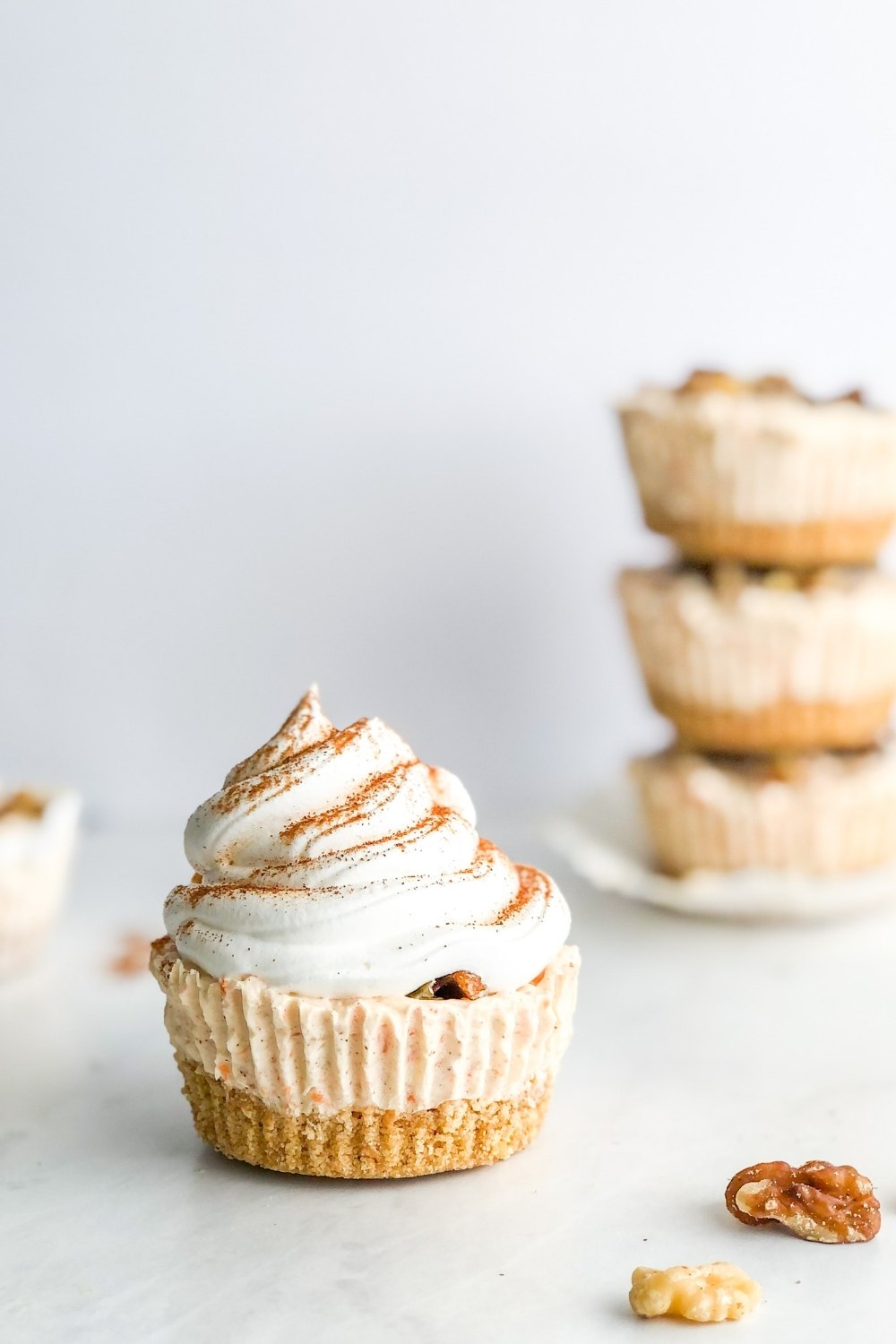 mini carrot cake cheesecake topped with whipped cream and cinnamon
