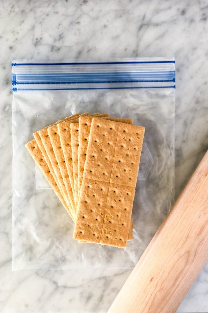 graham crackers in a ziploc bag with a rolling pin