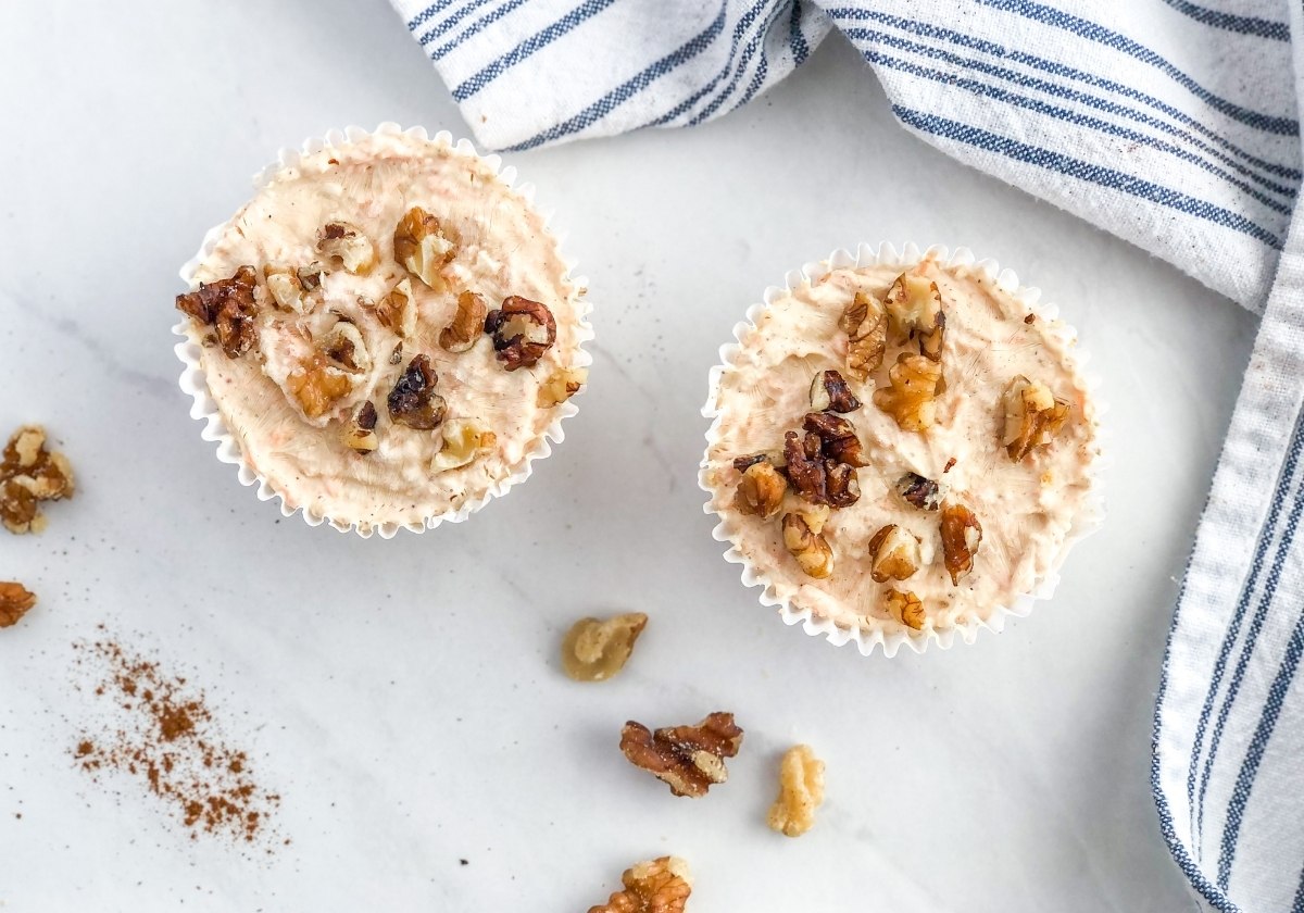 mini no bake carrot cake cheesecakes with a striped kitchen towel and chopped walnuts