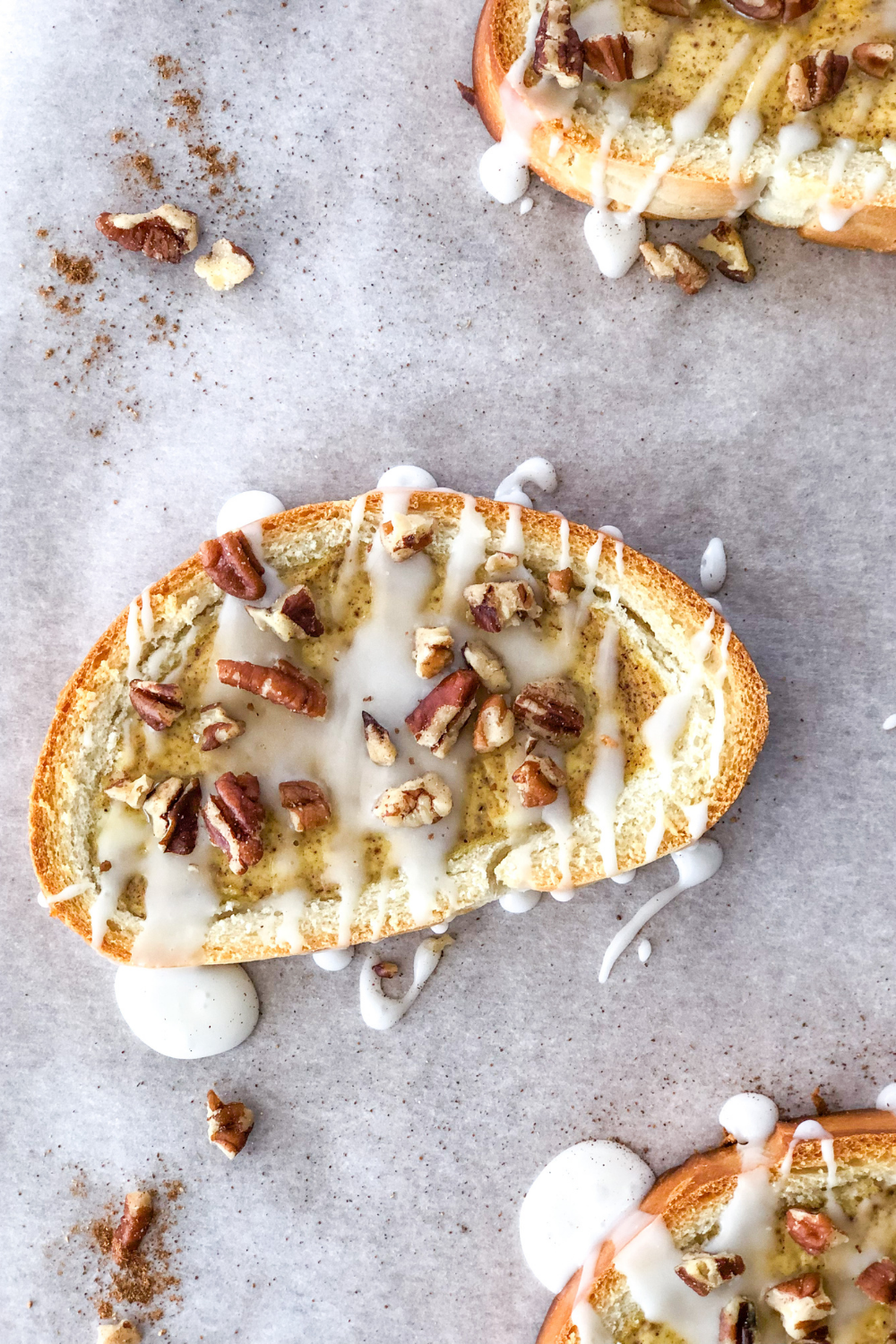 chai custard toast with pecans and icing on parchment paper