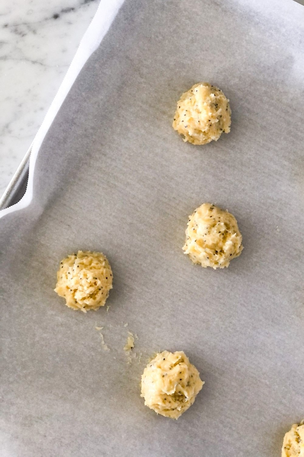 lemon mascarpone cookie dough balls on a parchment paper lined sheet pan
