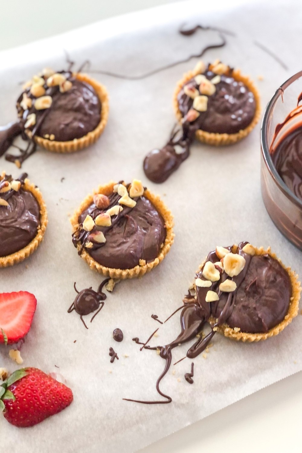 mini tarts with chocolate drizzle, chopped hazelnuts, and sliced strawberries