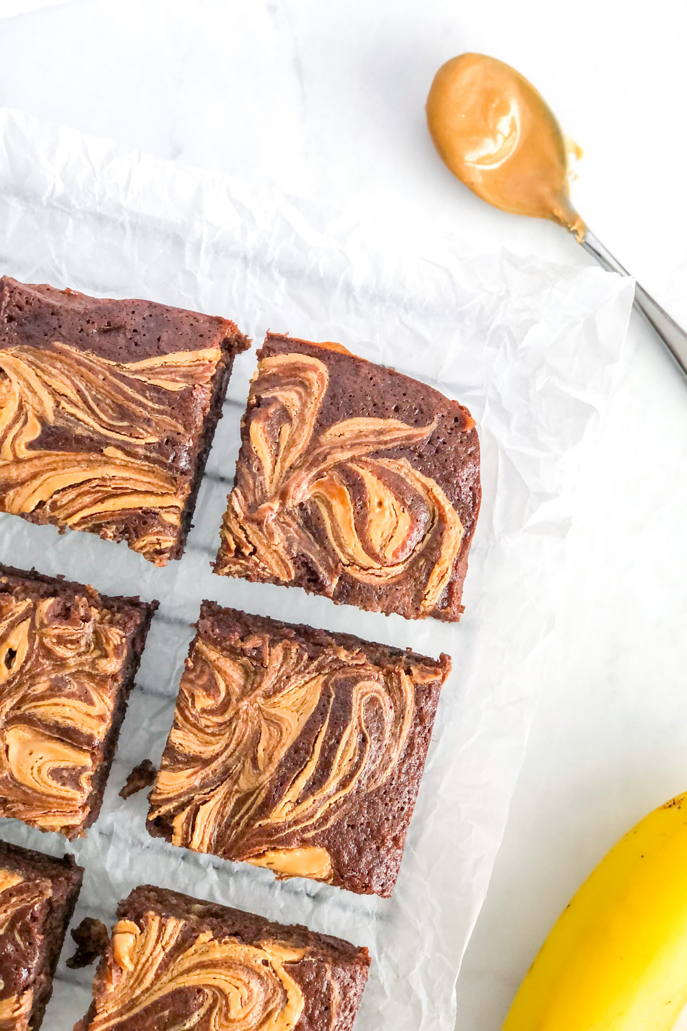 banana brownies on parchment paper with a spoonful of peanut butter