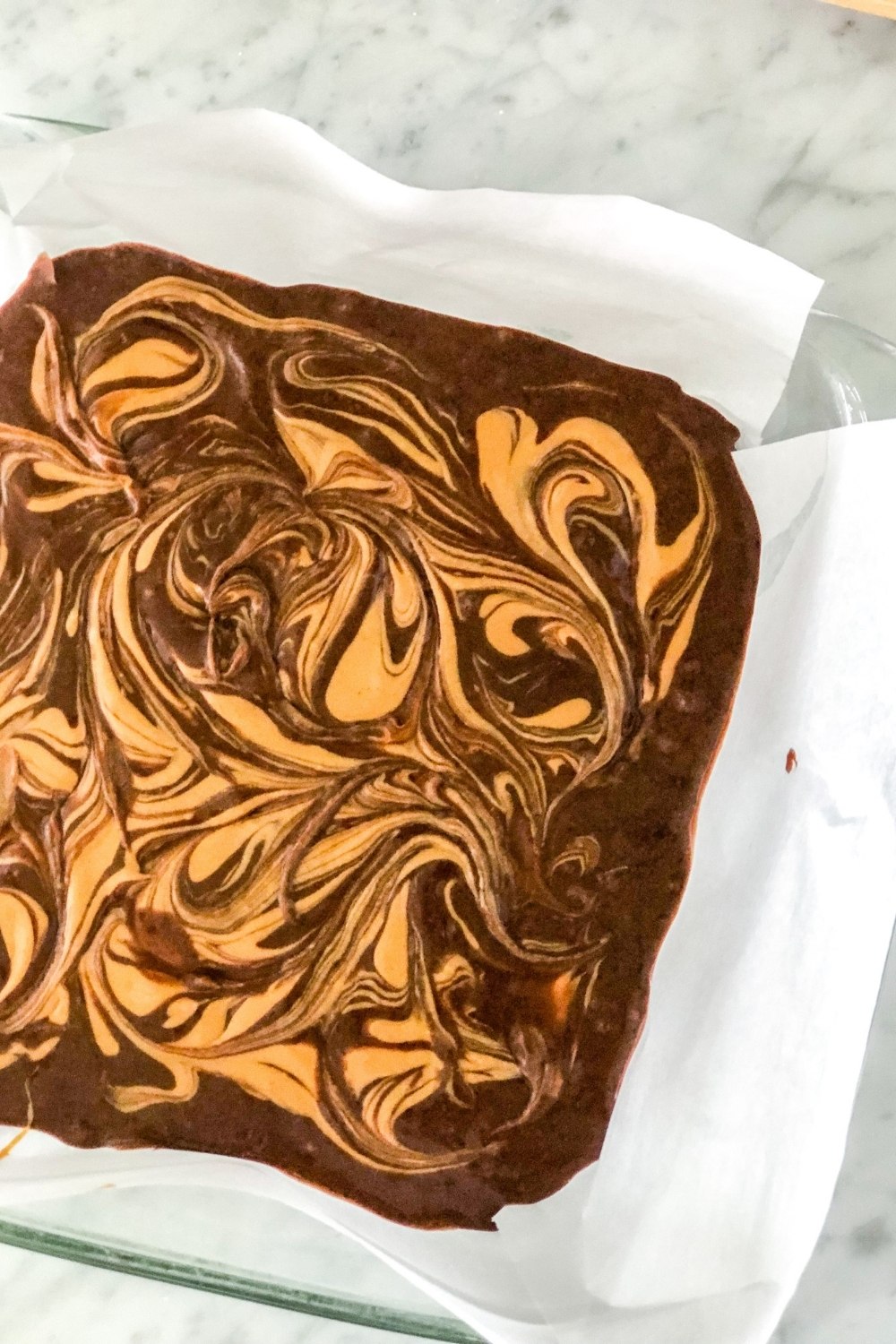 brownie batter with peanut butter swirl in a glass baking pan