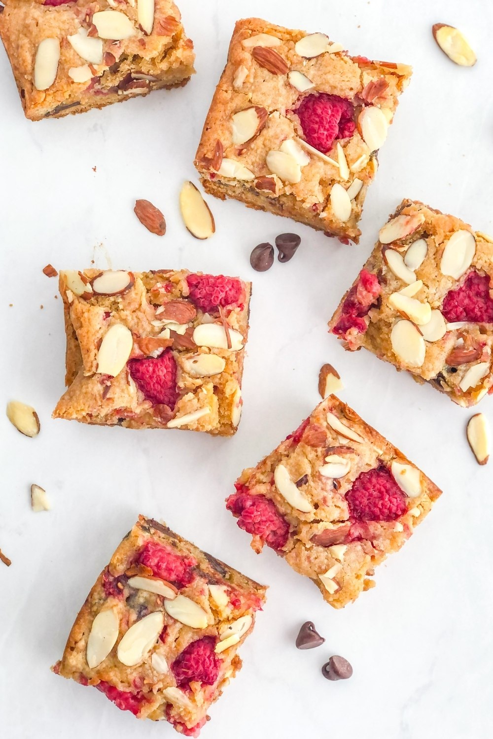 raspberry almond blondies with slivered almonds and dark chocolate chips on a marble surface