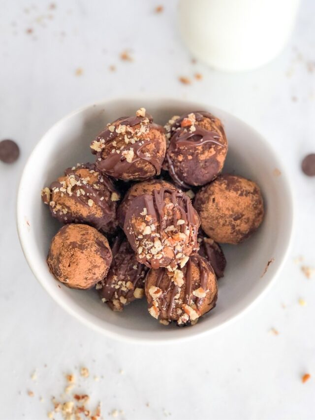 white bowl filled with cocoa pecan truffles with a glass of milk behind it