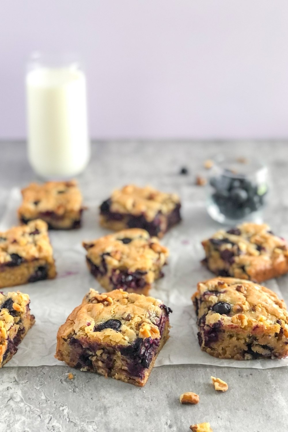 blueberry blondies with walnuts and a glass of milk in the background