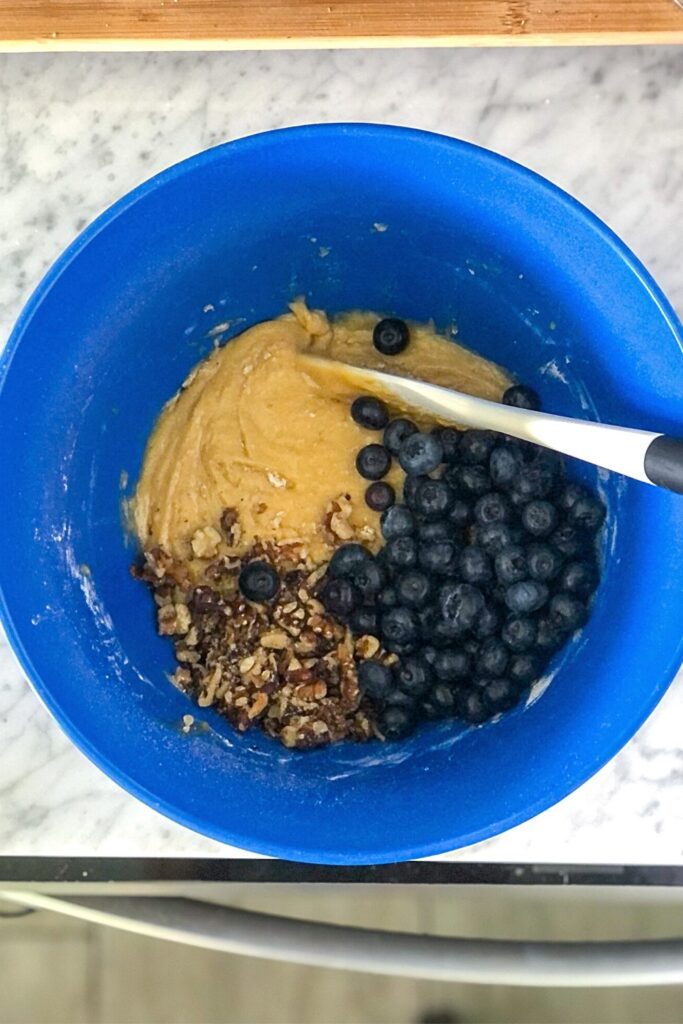 blondie batter with walnuts and blueberries in a blue mixing bowl