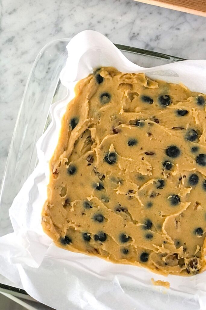 blueberry walnut blondie batter in a square glass baking pan