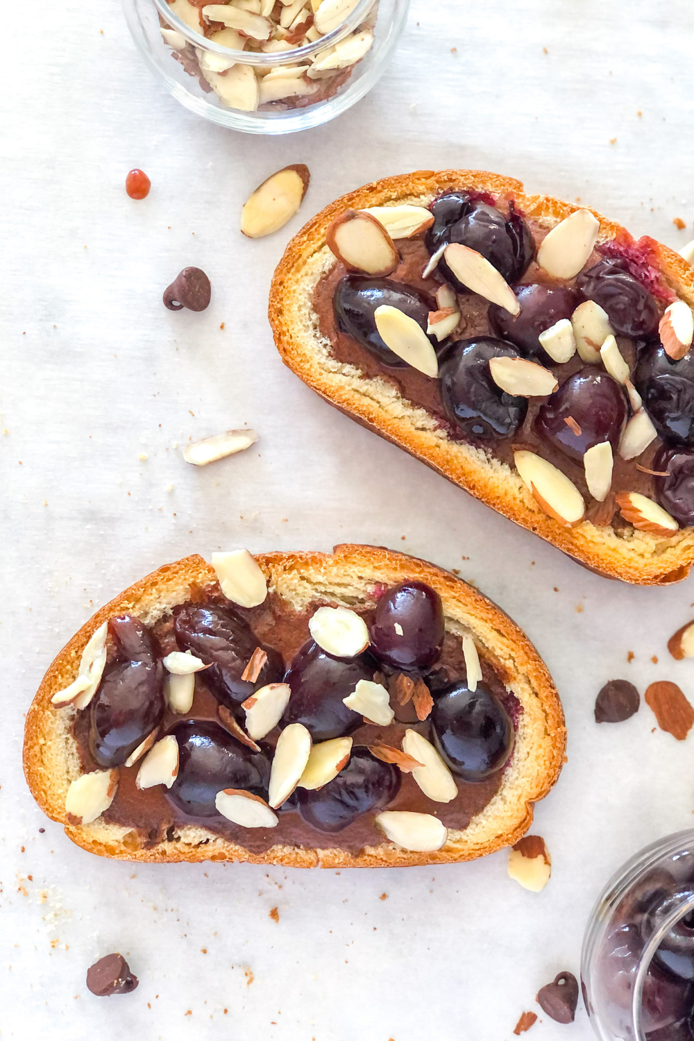chocolate custard toast with cherries and almonds on parchment paper