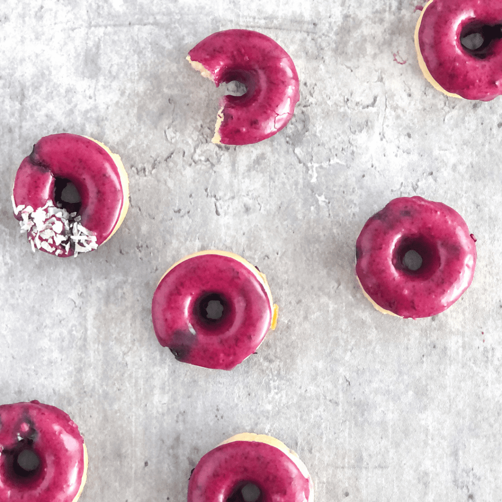 mini blueberry donuts with purple blueberry glaze on a grey background