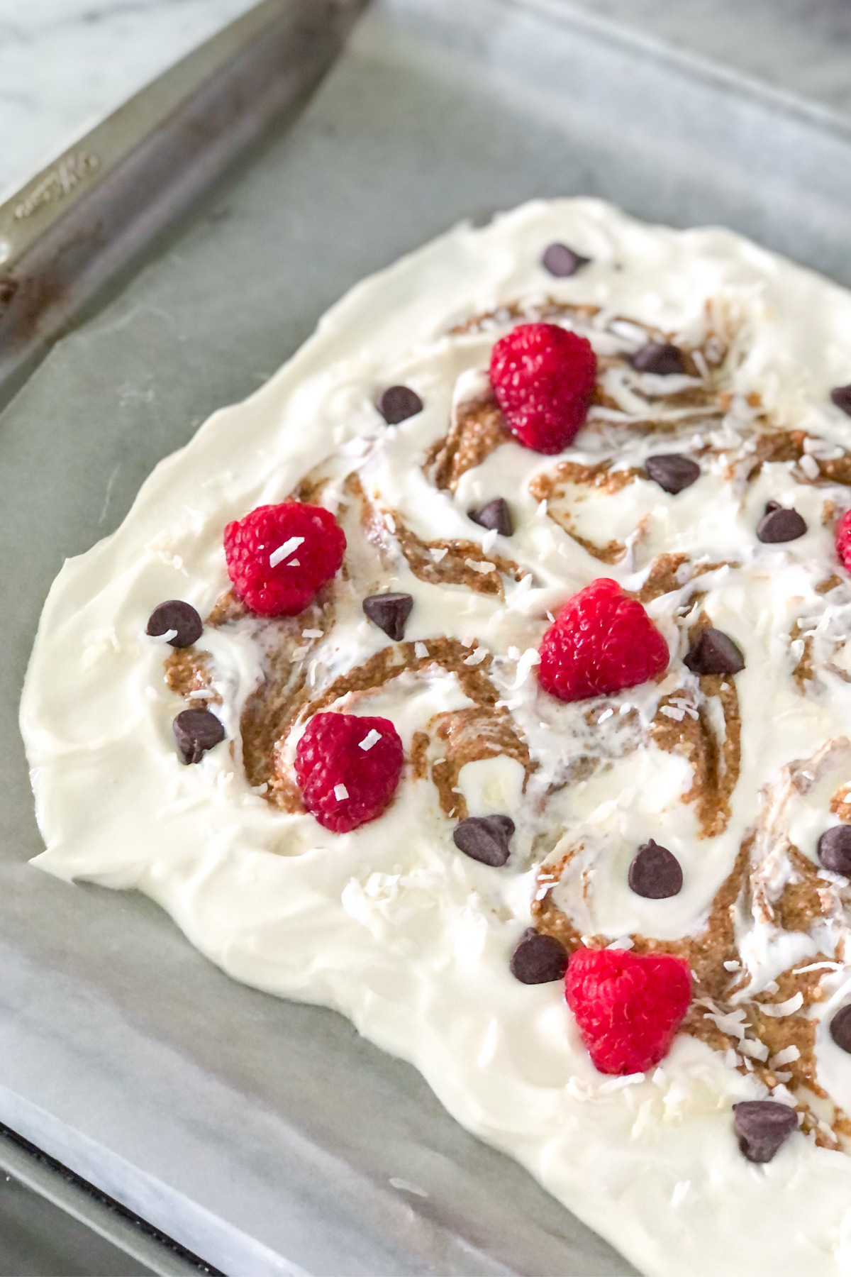 Greek yogurt with toppings on sheet pan before freezing