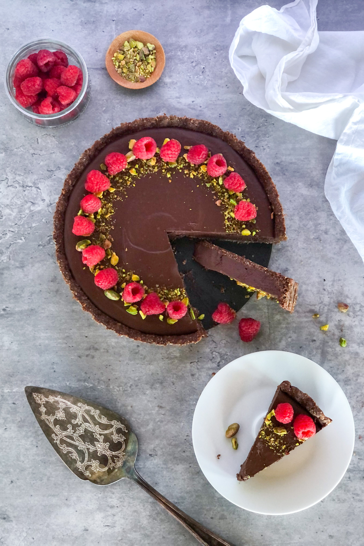 sliced dark chocolate raspberry tart with pistachios