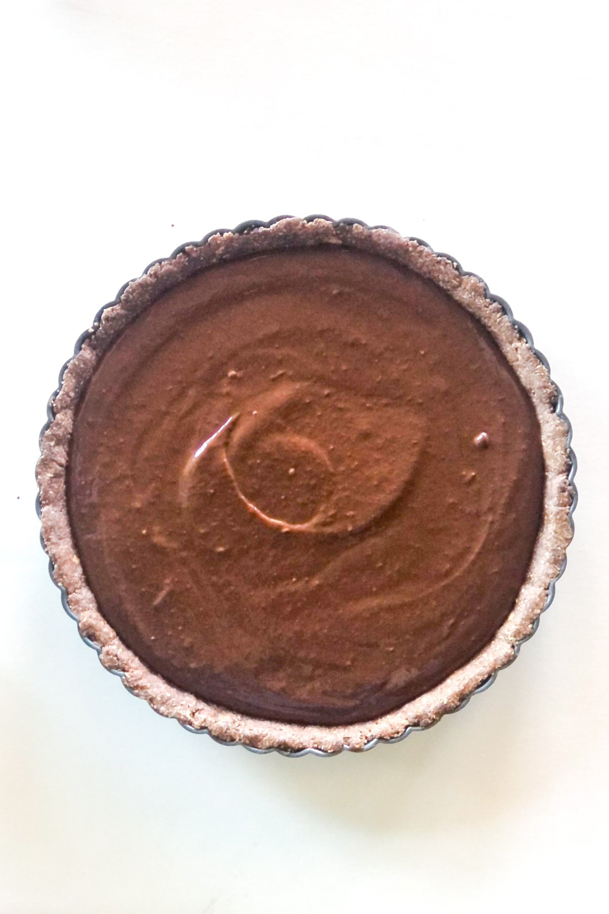 dark chocolate raspberry tart filling poured into the oat flour crust