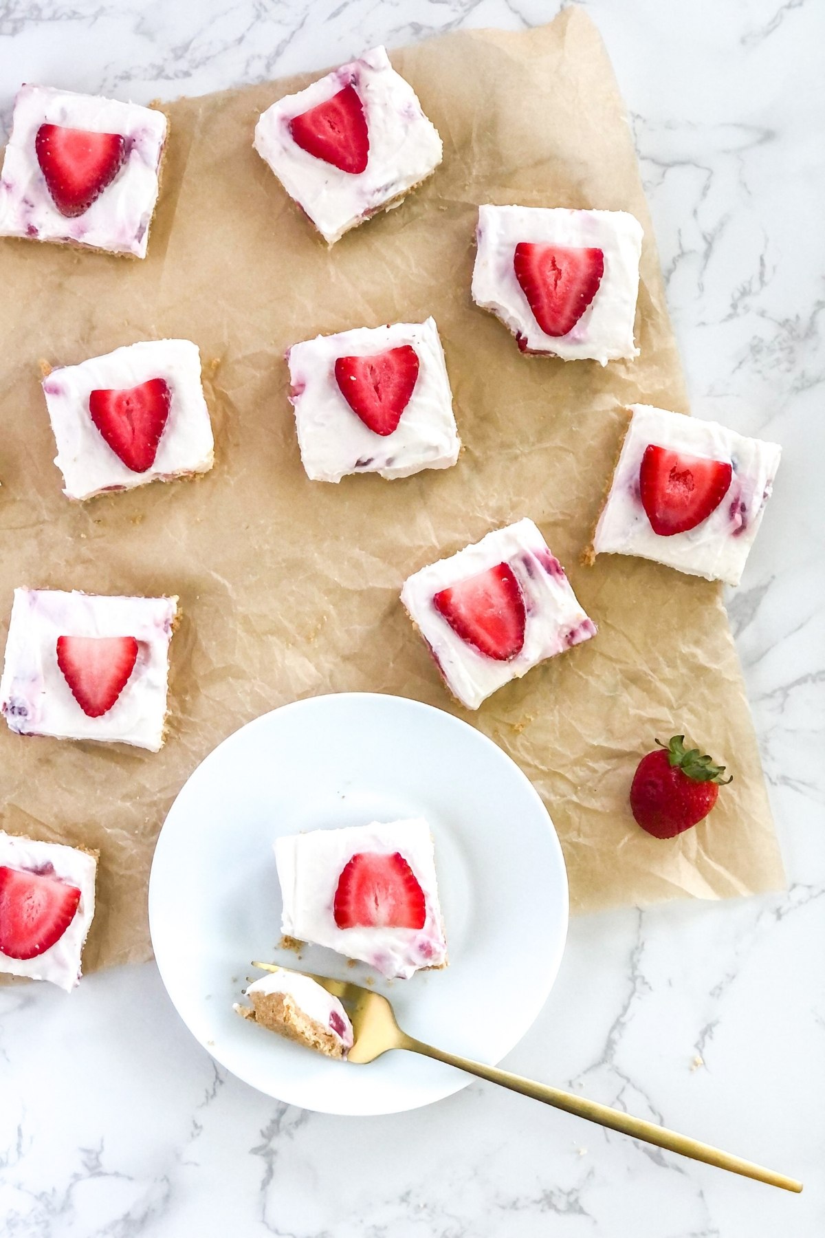 strawberry white chocolate cheesecake bars on parchment paper