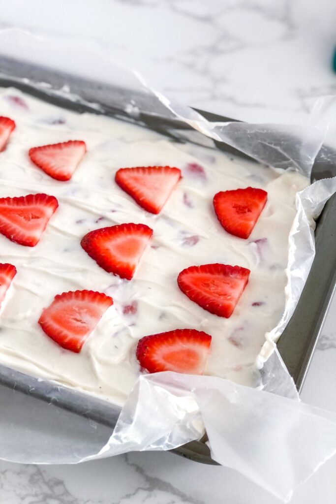 no bake cheesecake bars in a pan with strawberries on top