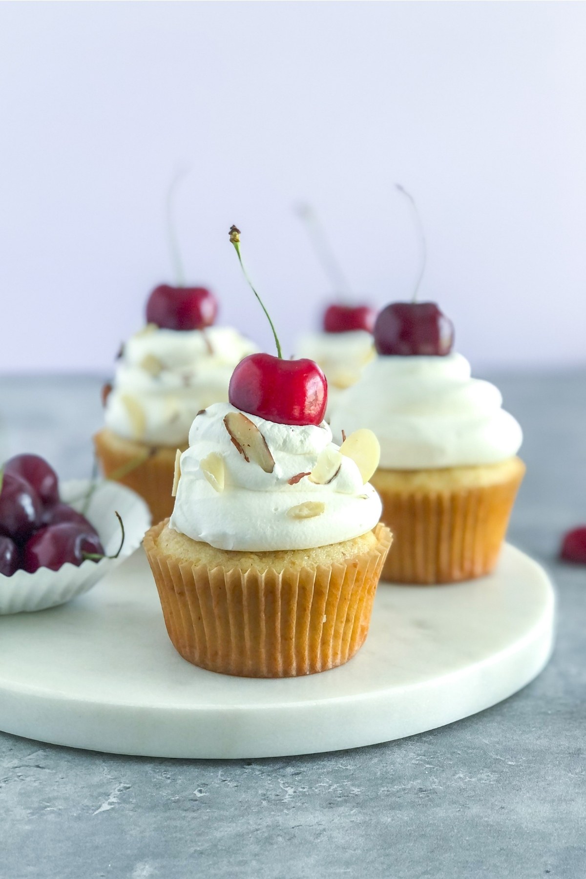 almond cherry cupcakes with whipped cream and a cherry on top