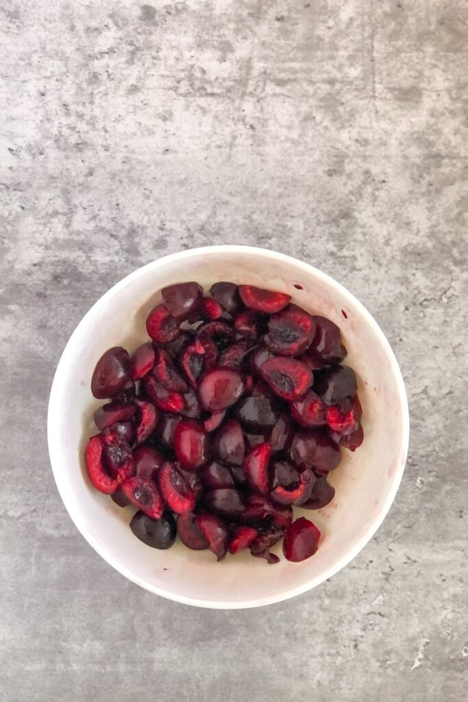 sliced fresh cherries with maple syrup in a white bowl