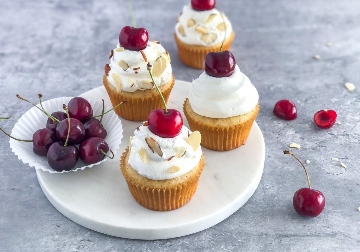 cherry almond cupcakes with whipped cream and a cherry on top
