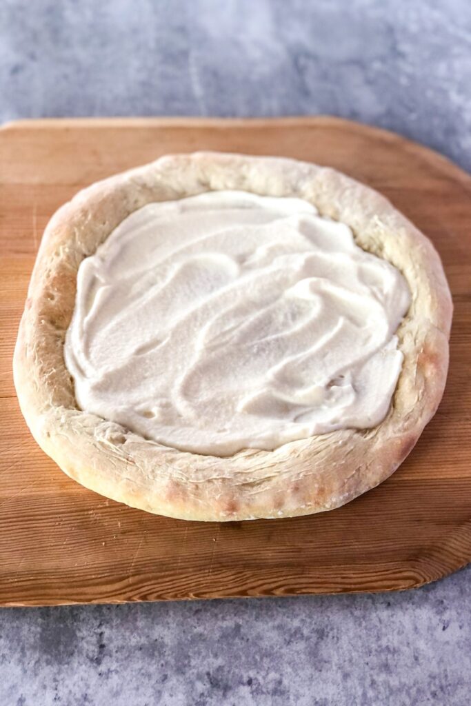 baked pizza crust with mascarpone yogurt sauce spread on top