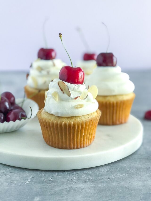almond cherry cupcakes with whipped cream and a cherry on top