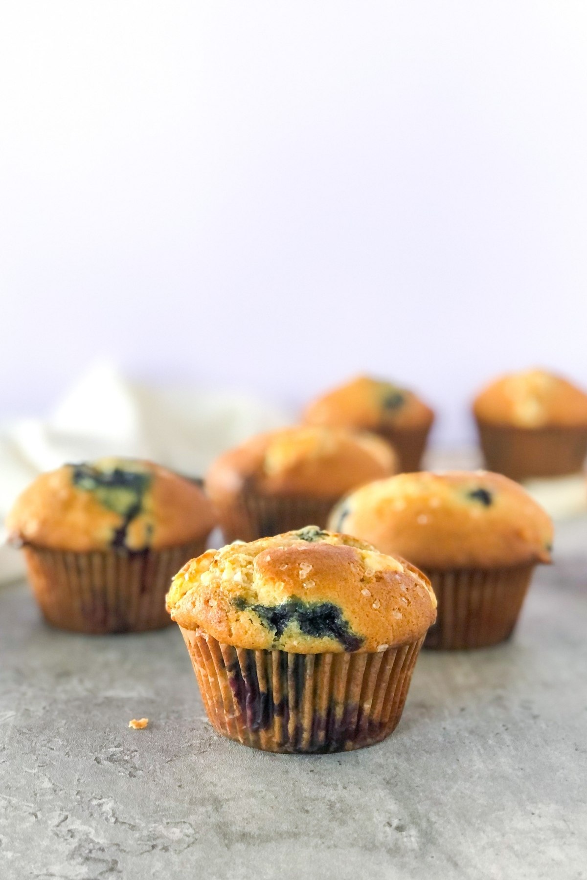 white chocolate muffins with blueberries in front of a white linen napkin