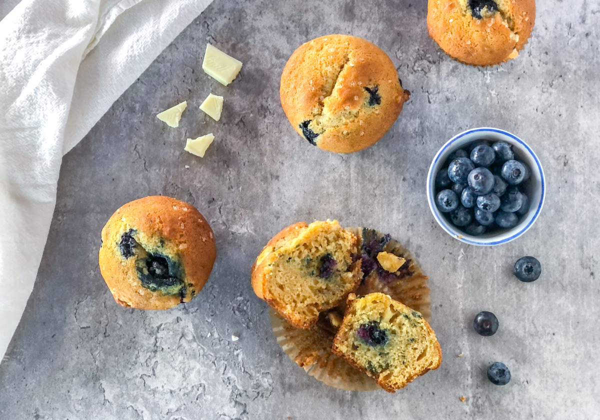 blueberry white chocolate muffins with a small bowl of blueberries