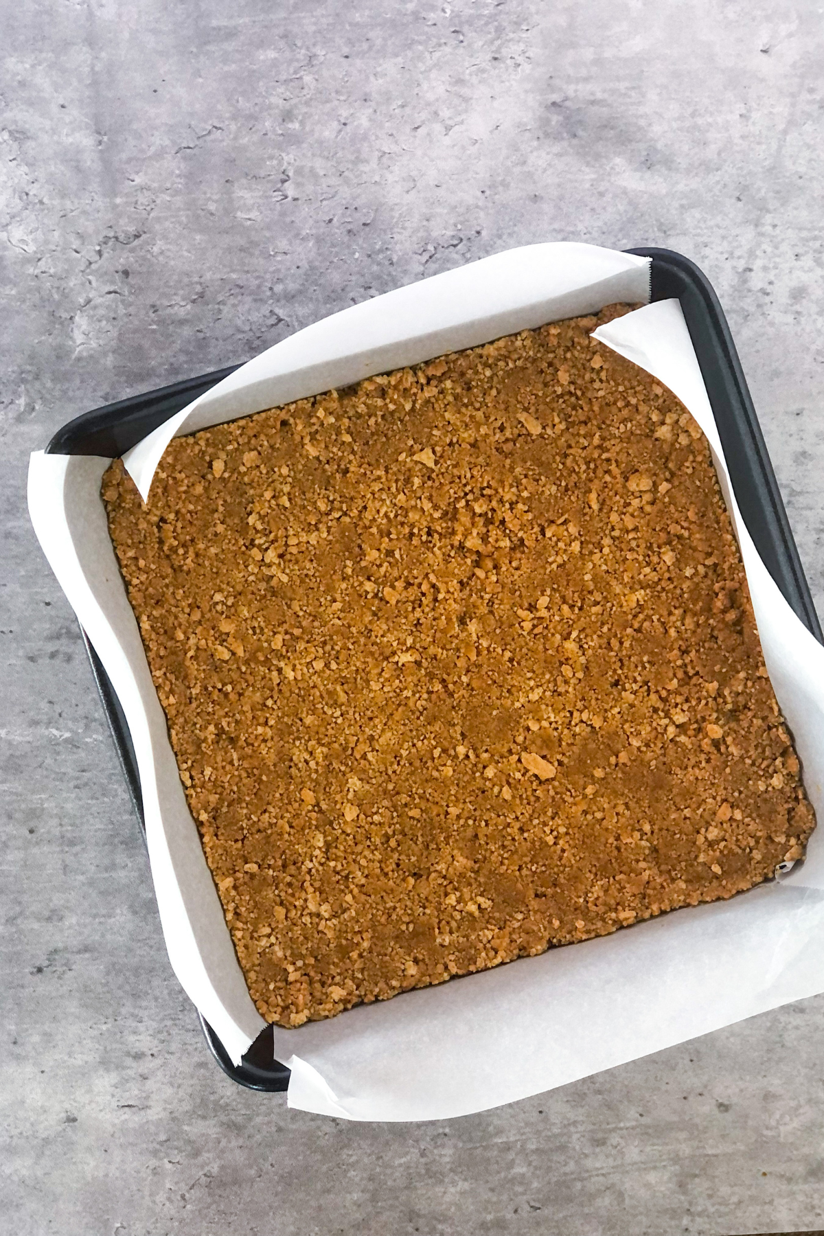 graham cracker crust in a square metal pan