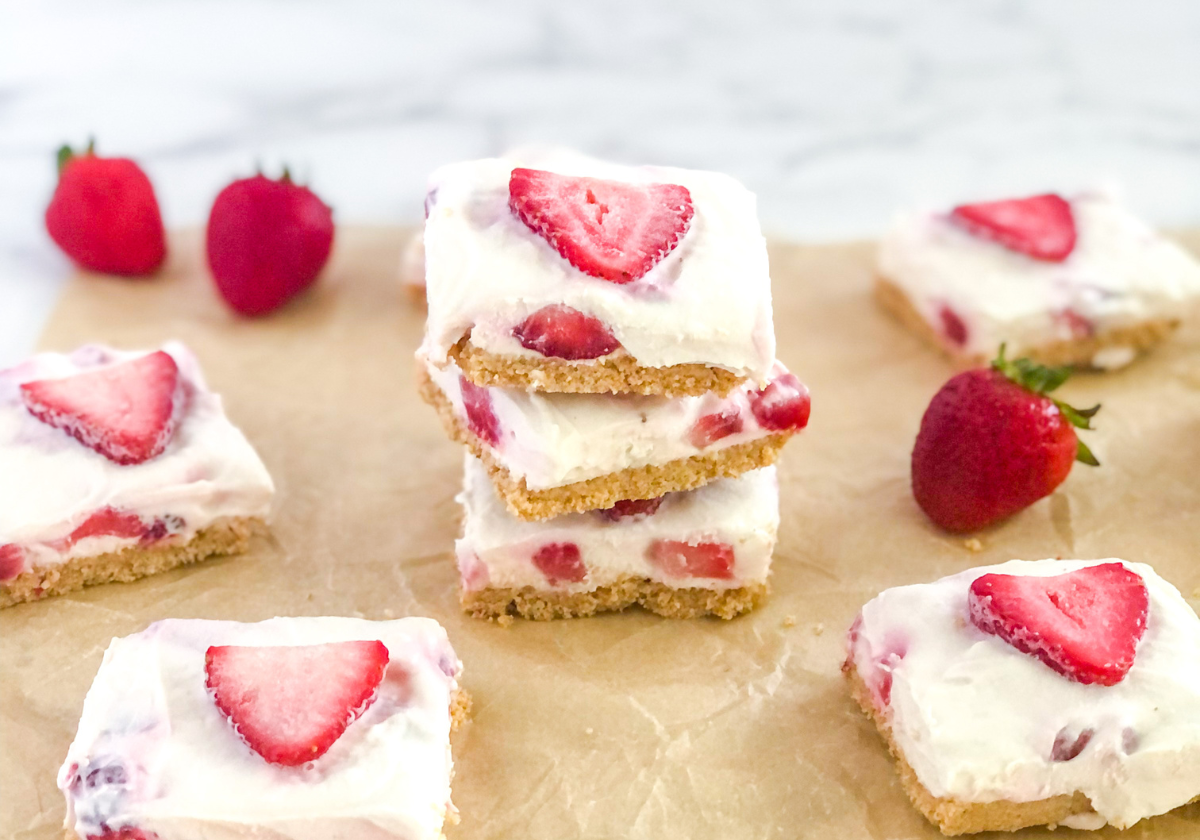 stack of no bake strawberry cheesecake bars on parchment paper