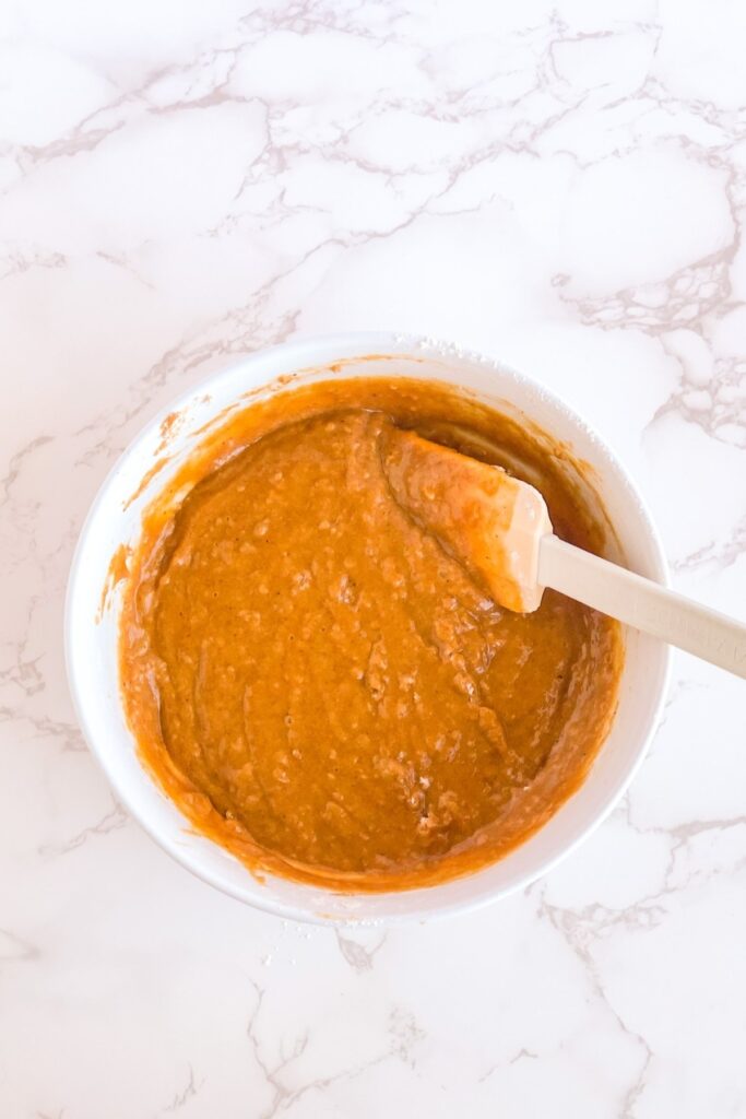 pumpkin batter in a white bowl with a spatula