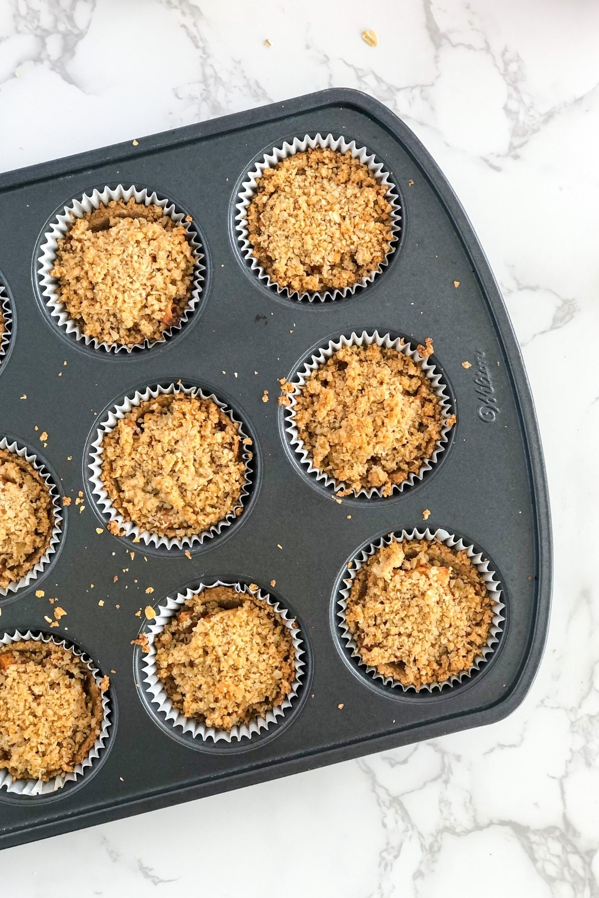 crumb topping on apple tarts in a muffin tin