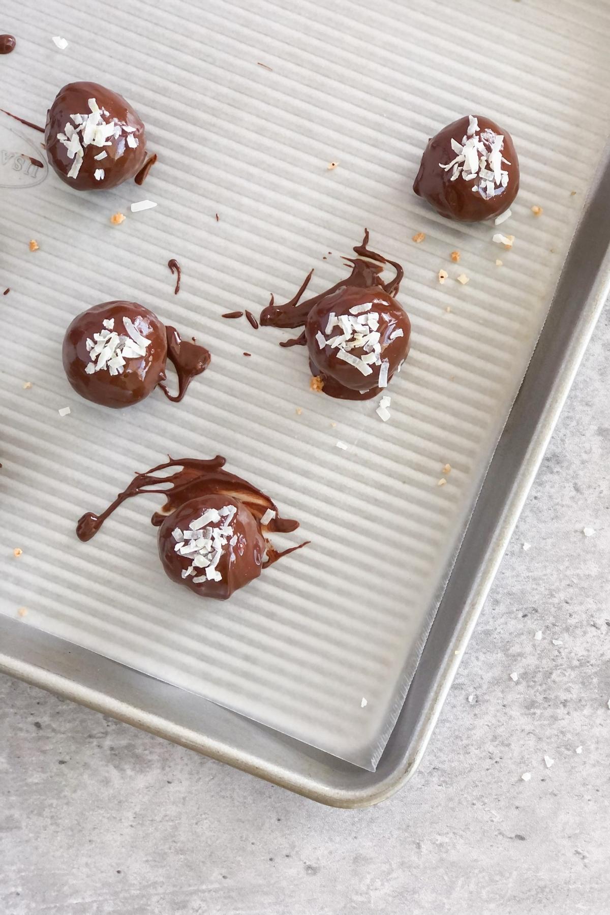 chocolate coconut bites with shredded coconut on top on a sheet pan