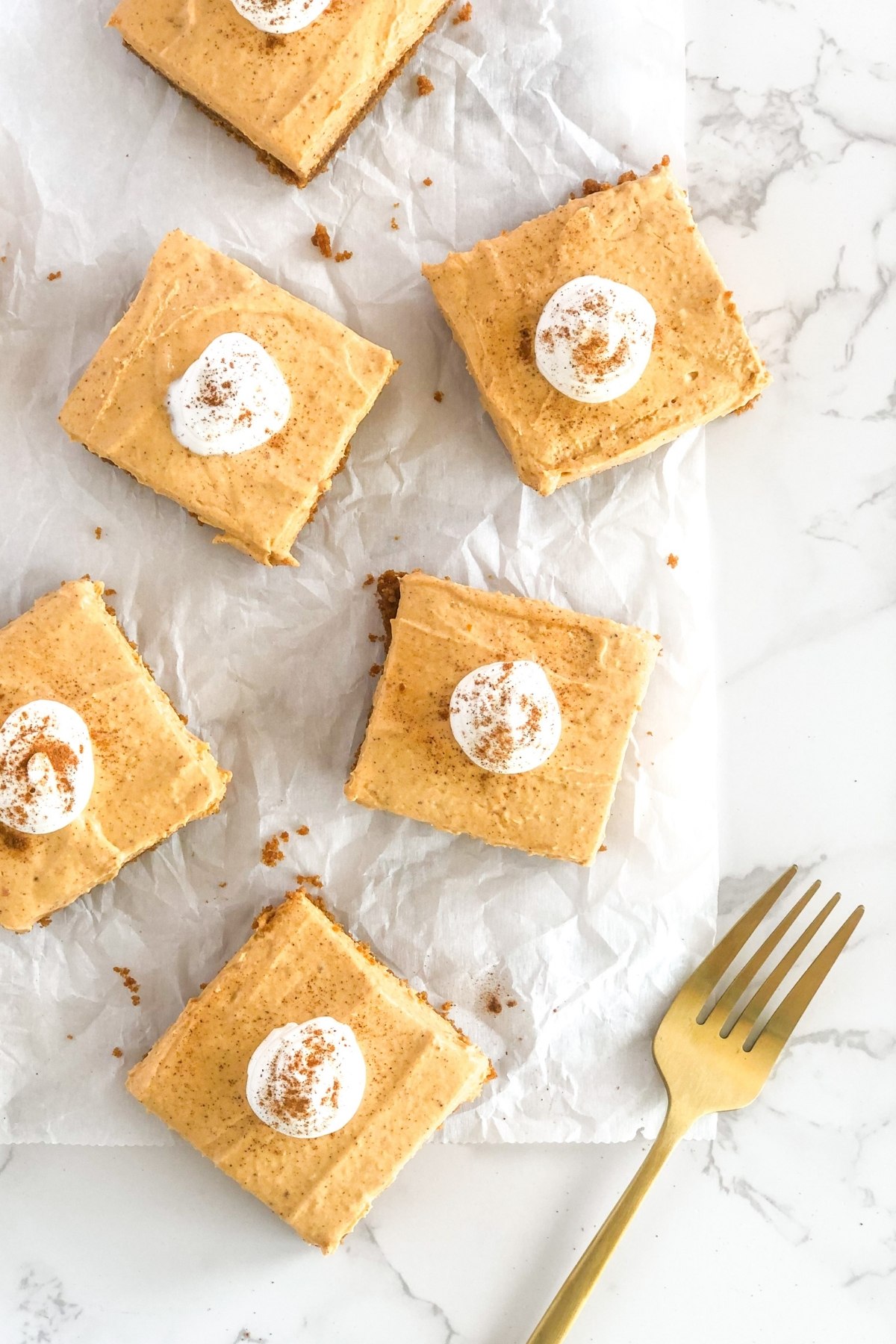 pumpkin cheesecake bars topped with whipped cream and cinnamon