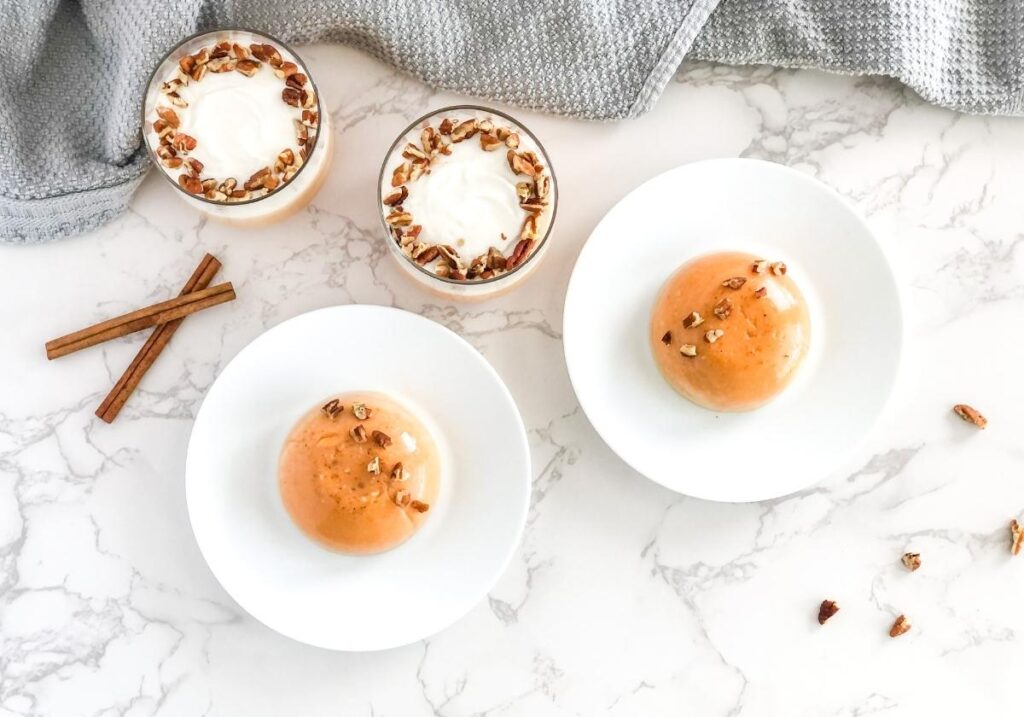 pumpkin panna cotta with maple syrup and pecans on a white marble background with a grey kitchen towel