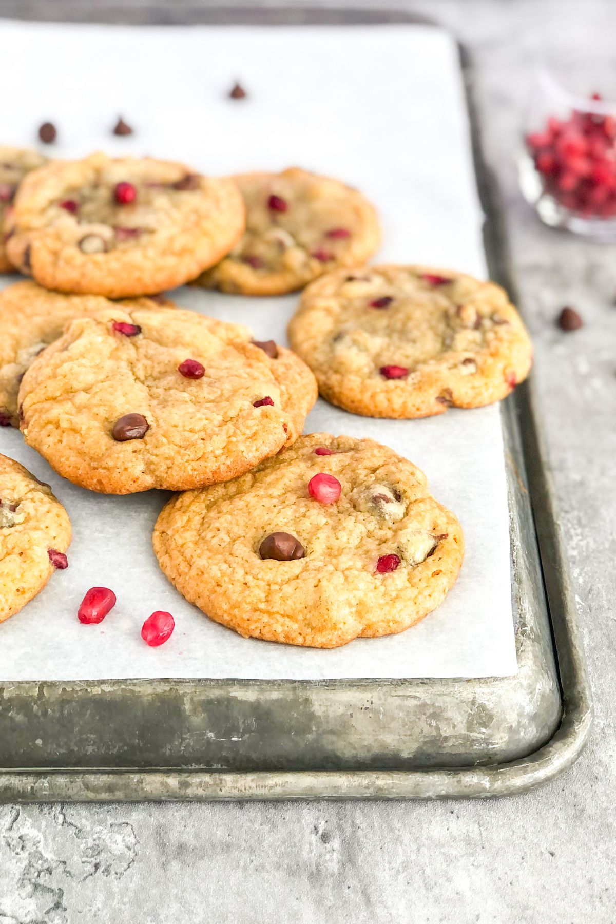 chocolate chip pomegranate cookies on a metal sheet pan with parchment paper
