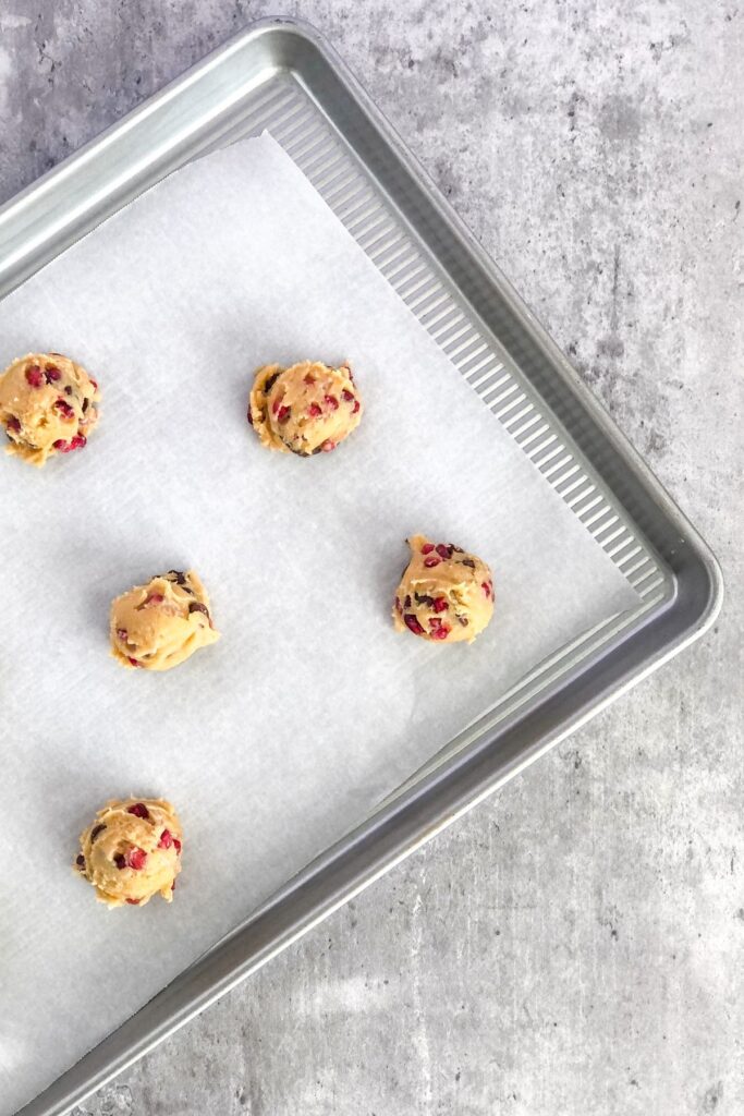 cookie dough scooped onto a baking pan lined with parchment paper