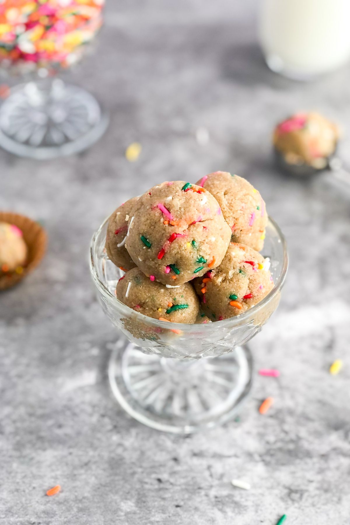 edible sugar cookie dough with sprinkles and a glass of milk