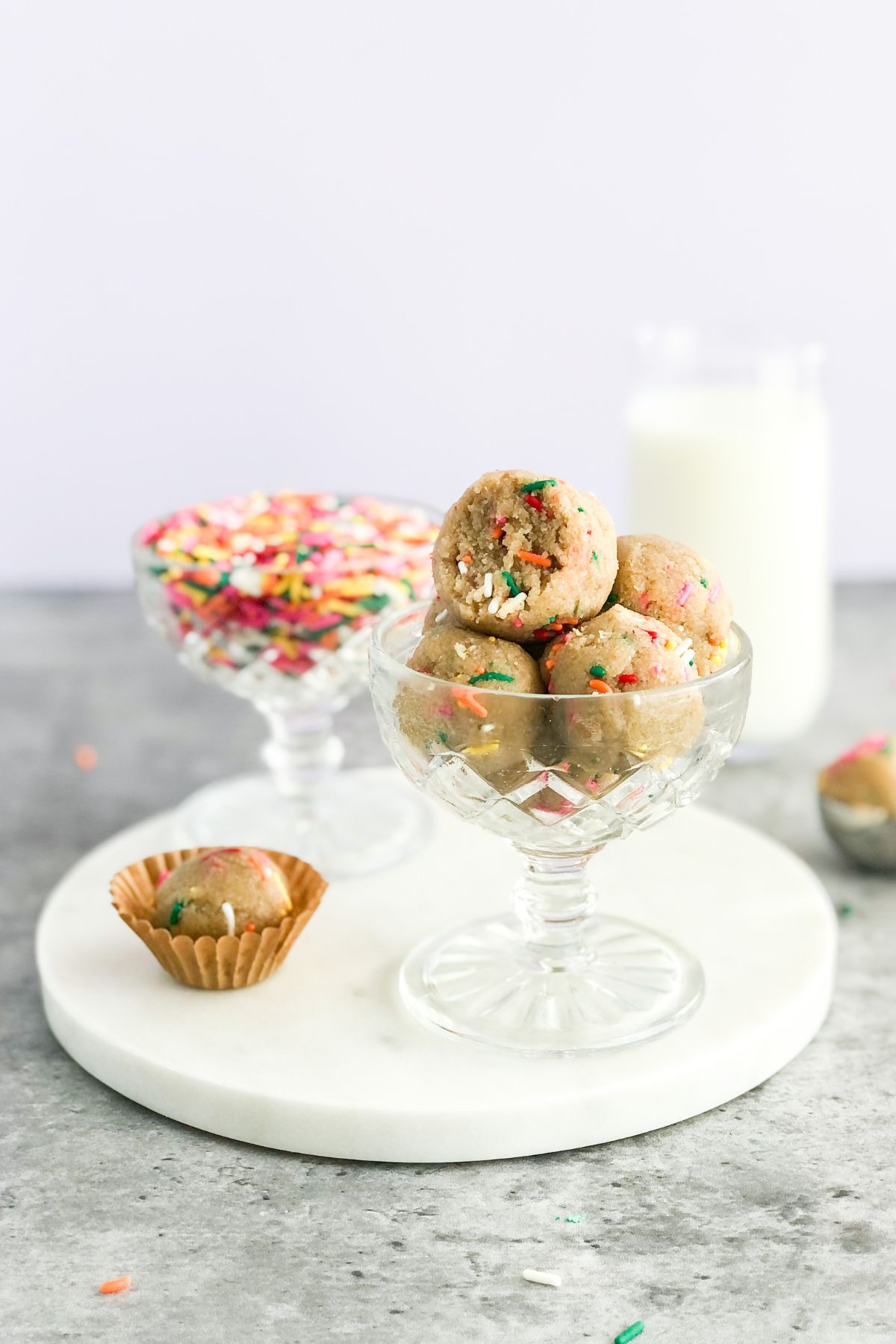 edible sugar cookie dough balls in a glass with milk and sprinkles