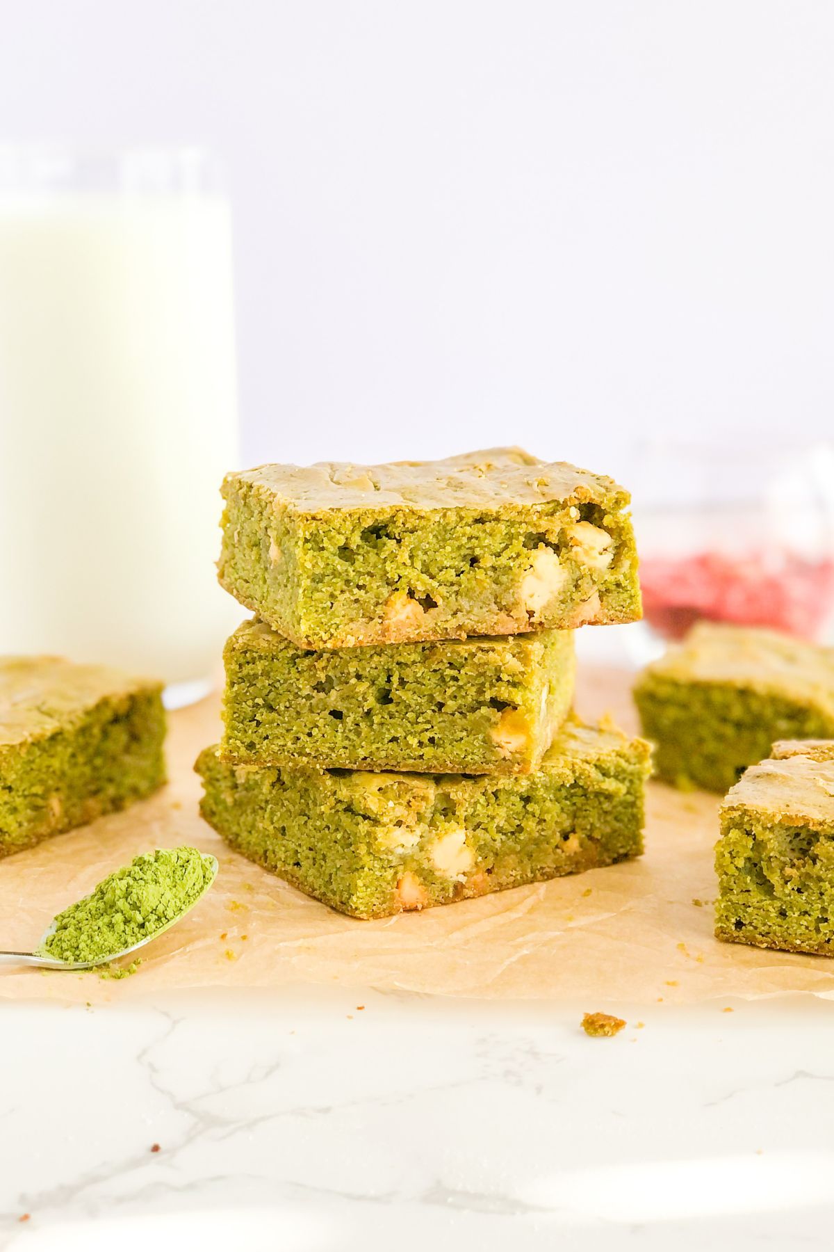 stack of matcha blondies with white chocolate chips and a glass of milk