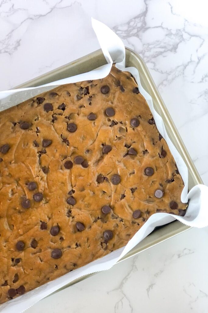 cookie dough in a baking pan with parchment paper
