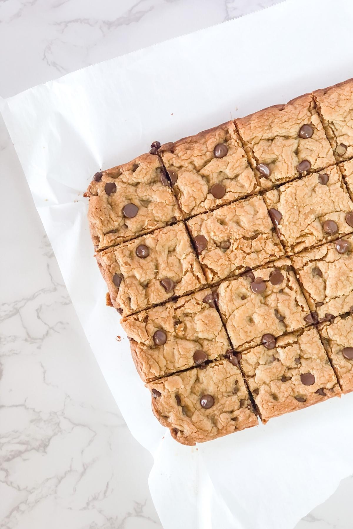 peanut butter chocolate chip cookie bars sliced on parchment paper